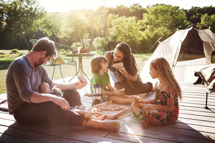 Rodina s třemi dětmi při jídle v přírodě s brýlovými čočkami Varilux Physio